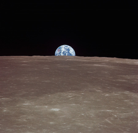 Một bức ảnh chụp Trái đất trong nền trông rất nhỏ. Bề mặt của mặt trăng ở phía trước, vì vậy Trái đất đang nhô lên trên mặt trăng.
